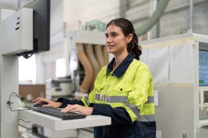 Une femme ingénieure utilisant un ordinateur pour faire fonctionner une machine à commande numérique