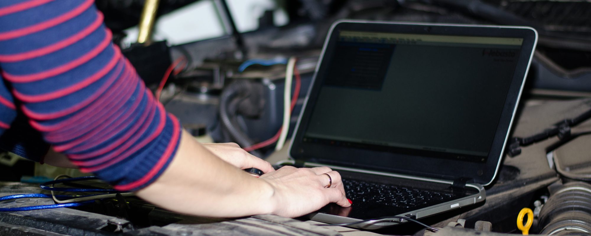 A car expert uses a laptop for automatic diagnostics. Computer diagnostics of a car engine. Expert girl, female hand on a laptop keyboard. Close-up.