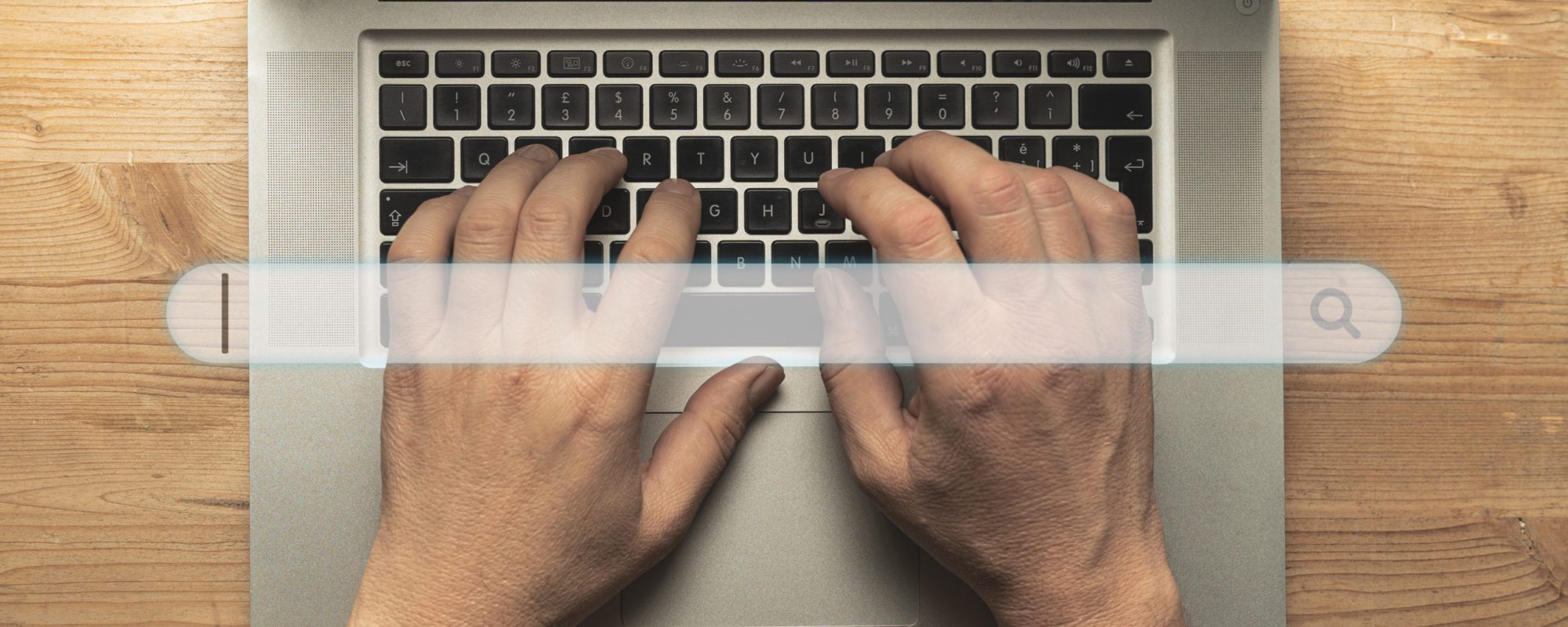 Fingers typing on a tablet computer on a wooden table. Search ba