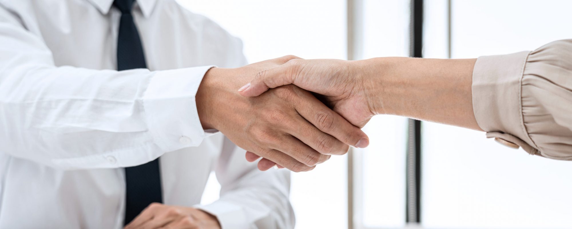 Woman employer is shaking hands to congratulate with the new employee after successful with job interview and signing contract in meeting room at office